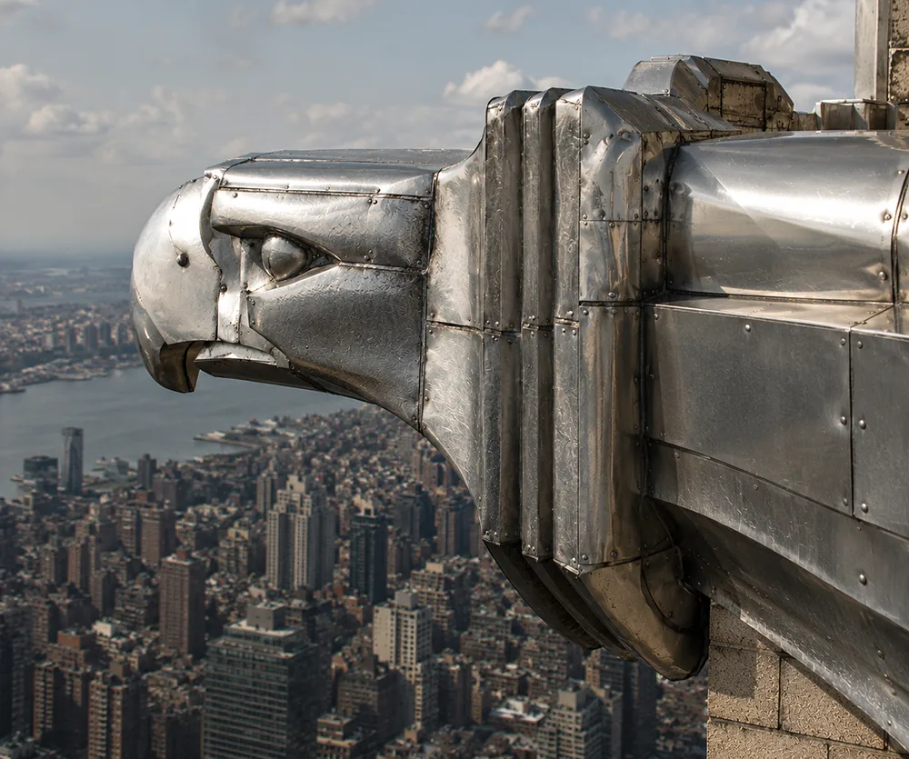 Close-up of a stainless steel eagle gargoyle on the Chrysler Building overlooking the New York City skyline