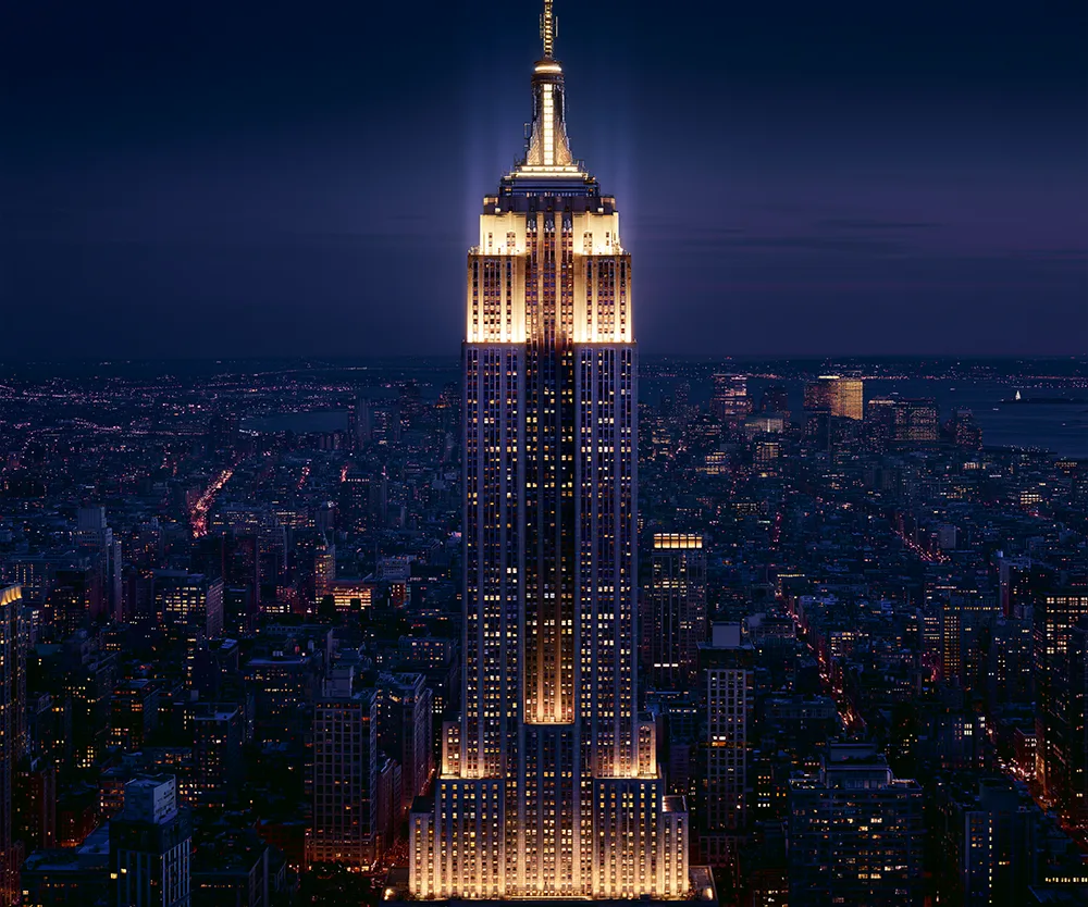 The Empire State Building illuminated at night above the Manhattan skyline